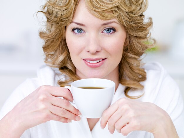 Nahaufnahmeporträt der hübschen jungen schönen blonden Frau mit Tasse Kaffee