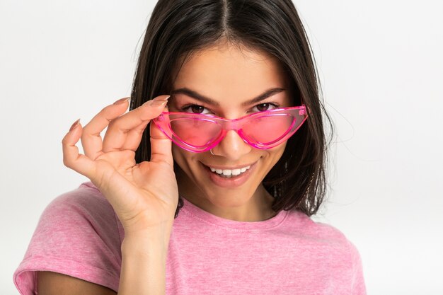 Nahaufnahmeporträt der hübschen lächelnden emotionalen Frau im rosa Hemd und in der stilvollen Sonnenbrille, weiße Zähne, positive Aufstellung isoliert