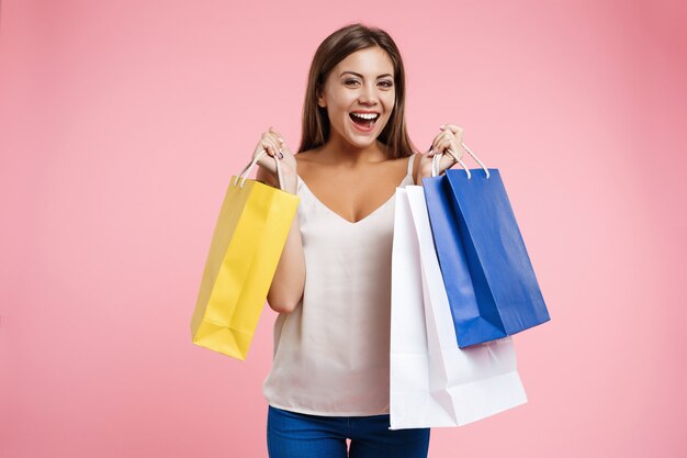 Nahaufnahmeporträt der jungen glücklichen Frau, die Taschen beim Einkaufen hält