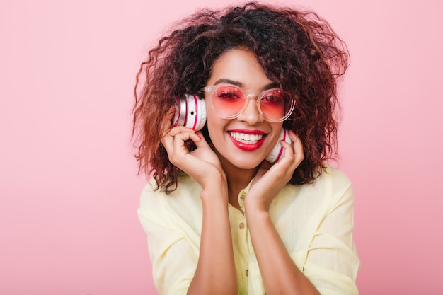 Nahaufnahmeporträt der prächtigen schwarzhaarigen Frau mit der braunen Haut, die mit Musik kühlt. entzückendes weibliches Mulattenmodell mit aufrichtigen Gefühlen.