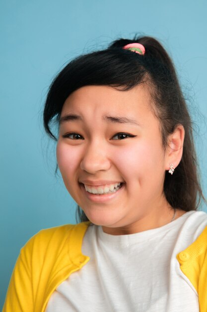 Nahaufnahmeporträt des asiatischen Teenagers lokalisiert auf blauem Raum