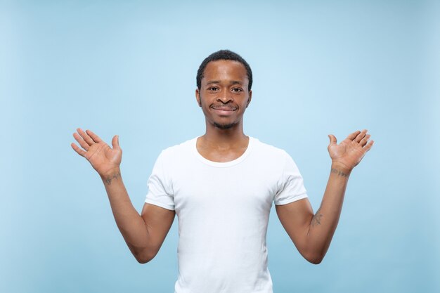 Nahaufnahmeporträt des jungen afroamerikanischen Mannes im weißen Hemd. Leere Leiste zeigend, zeigend, wählend, einladend.