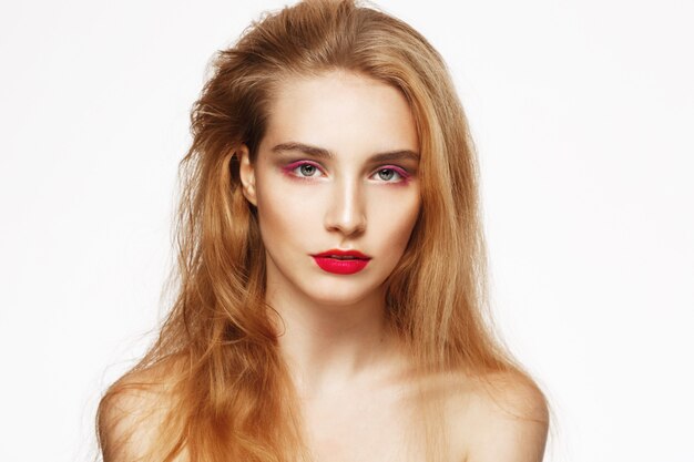 Nahaufnahmeporträt des jungen schönen selbstbewussten Mädchens mit hellem Make-up. weiße Wand. Isoliert. Schönheitskonzept.
