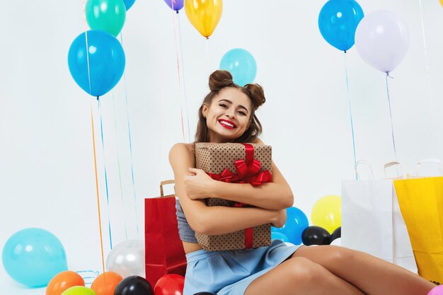 Nahaufnahmeporträt des lächelnden Mädchens, das große Geschenkbox umarmt