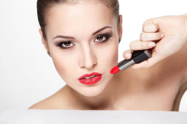 Nahaufnahmeporträt des sexy kaukasischen jungen Frauenmodells mit glamourösen roten Lippen, hellem Make-up, Augenpfeil-Make-up, reinem Teint mit rotem Lippenstift. Perfekt saubere Haut