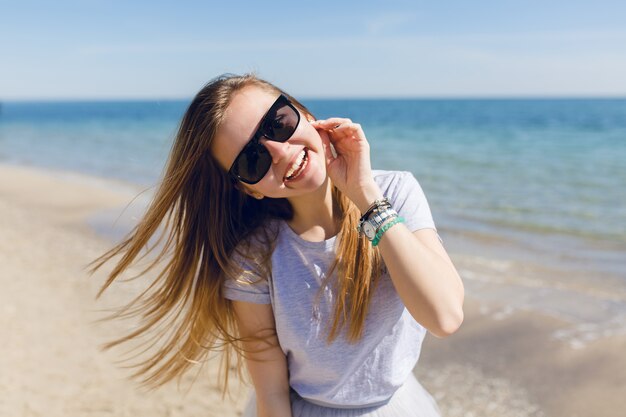 Nahaufnahmeporträt einer jungen hübschen Frau mit langen Haaren, die auf dem Strand nahe Meer gehen