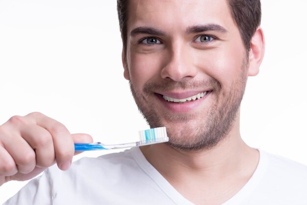 Nahaufnahmeporträt eines glücklichen jungen Mannes mit einer Zahnbürste - lokalisiert auf Weiß.