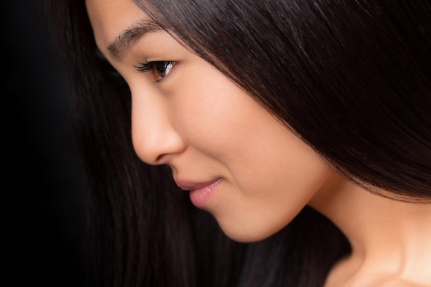 Nahaufnahmeprofil einer asiatischen Dame mit langen schwarzen Haaren, die im Studio posiert.