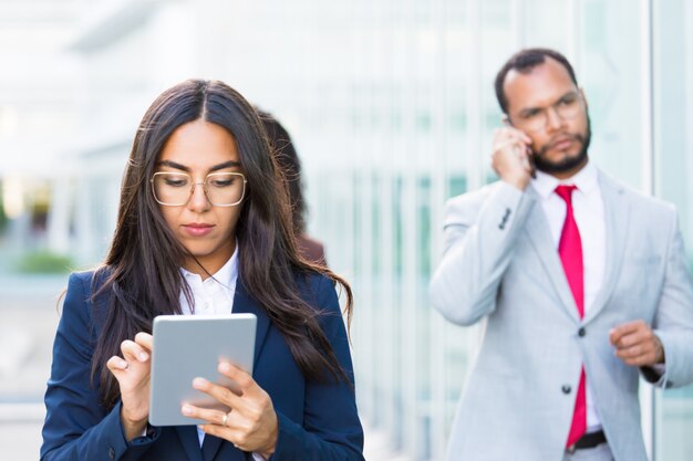 Nahaufnahmeschuß der fokussierten asiatischen Arbeitskraft, die Tablette verwendet