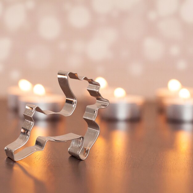 Nahaufnahmeschuss der Metallhirschdekoration mit unscharfen kleinen Kerzen auf dem Hintergrund