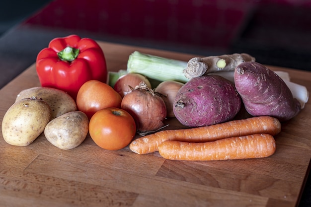 Kostenloses Foto nahaufnahmeschuss von süßkartoffel, tomate, zwiebel, karotten, pfeffer, kartoffel und ingwer auf einem holztisch