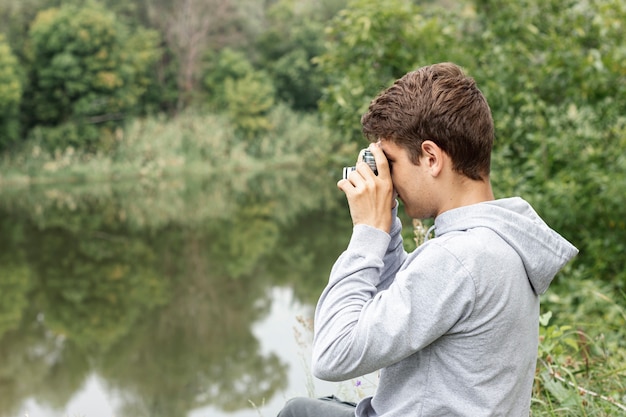 Nahaufnahmeschußjunge, der Fotos von einem See macht