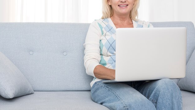 Kostenloses Foto nahaufnahmesmileyfrau mit laptop auf der couch