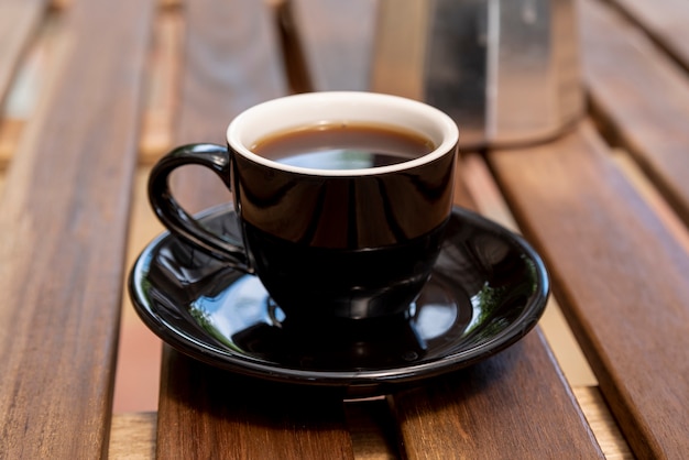 Nahaufnahmetasse kaffee mit hölzernem Hintergrund