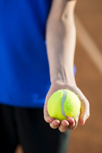 Nahaufnahmetennisball in der Hand gehalten