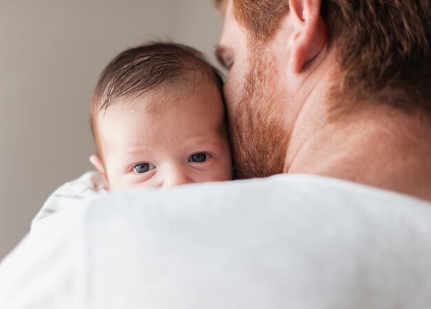 Nahaufnahmevater, der hintere Ansicht des Babys hält