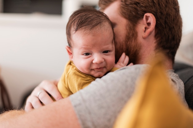 Nahaufnahmevati, der auf der Couch mit Baby sitzt