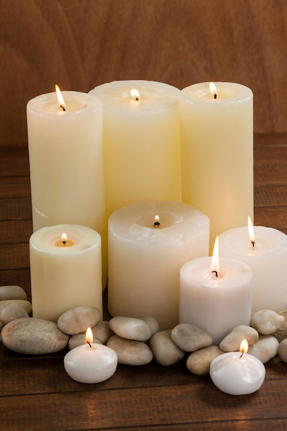 Nahaufnahmezubehör von weißen Kerzen und Kies Stein auf Holz