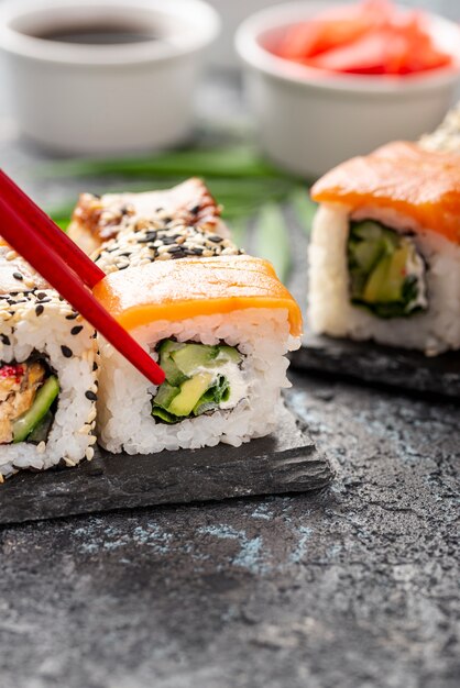 Nahaufnahmezusammenstellung von maki Sushirollen mit Essstäbchen auf Schiefer