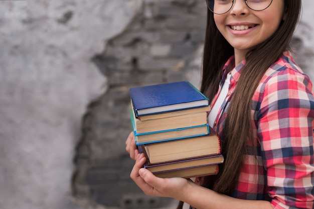 Nahes junges mädchen, das einen stapel bücher hält