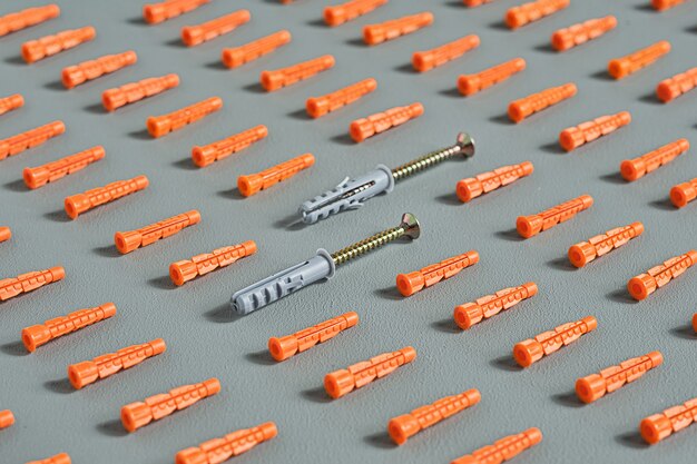 Nahtloses Muster von roten Plastikdübeln auf Grau