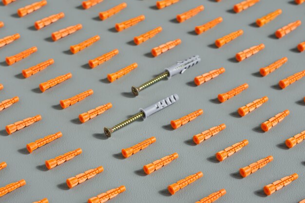 Nahtloses Muster von roten Plastikdübeln auf Grau