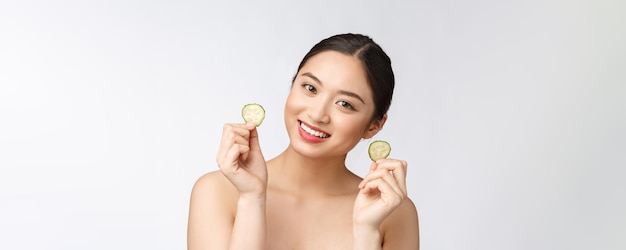 Natürliche hausgemachte frische Gurke Gesichtsaugenpolster Gesichtsmasken Asiatische Frau hält Gurkenpolster und Lächeln entspannen mit natürlichen hausgemachten