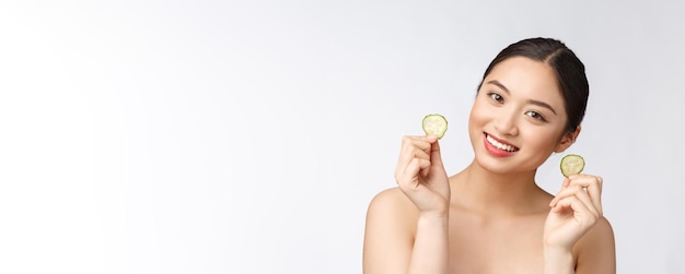 Natürliche hausgemachte frische Gurke Gesichtsaugenpolster Gesichtsmasken Asiatische Frau hält Gurkenpolster und Lächeln entspannen mit natürlichen hausgemachten