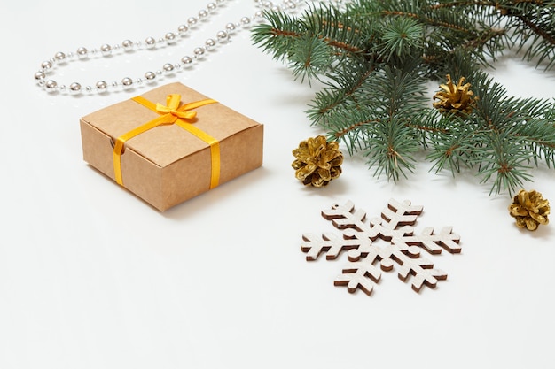 Natürlicher tannenzweig mit zapfen, einer geschenkbox und anderem weihnachtsschmuck auf weißem hintergrund
