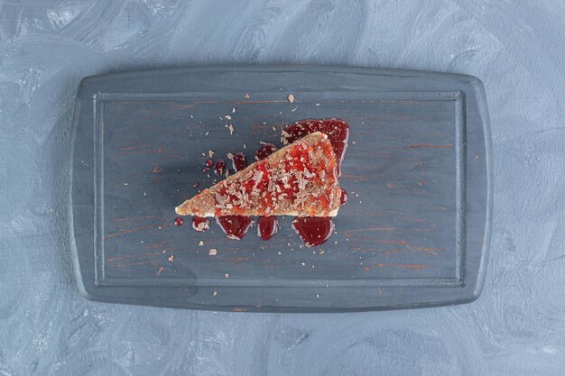 Navy Platte mit einem Stück Kuchen mit Erdbeersirup auf Marmoroberfläche gewürzt.