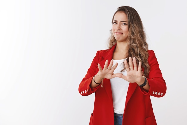 Nein danke ich passe. Porträt unzufriedenes Mädchen, das Abneigung ausdrückt, Antypie, Abneigung gegen winkende Handflächen, Ablehnungsgeste, Grimassieren, grobes widerstrebendes Angebot, angewidert, weiße Wand