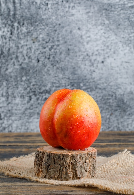 Nektarine mit sackstück, holzholz-seitenansicht auf hölzerner und schmuddeliger wand