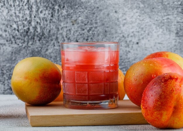 Nektarinen mit Saft auf grungy und Schneidebrett Tisch, Seitenansicht.