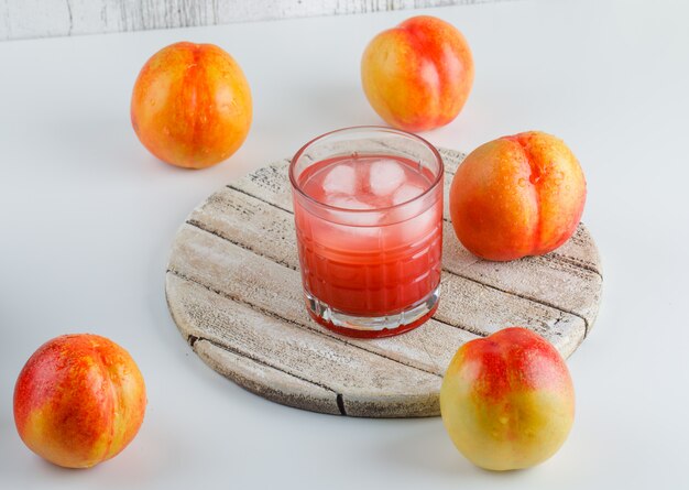 Nektarinen mit Saft, Schneidebrett, auf weißer und schmuddeliger Wand, Blickwinkel.