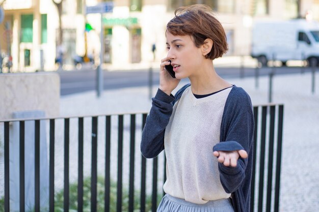 Nervöse Frau, die auf Smartphone geht und spricht