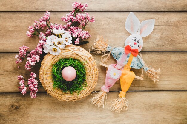 Nest in der Nähe von Blumen und Spielzeug Hase