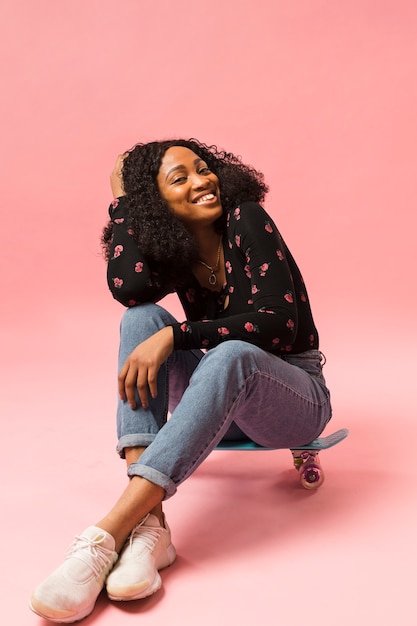 Kostenloses Foto nette afroamerikanische dame, die auf skateboard sitzt