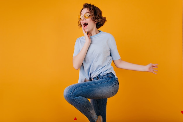 Nette dunkelhaarige Dame mit aufgeregtem Gesichtsausdruck, der in Jeans tanzt