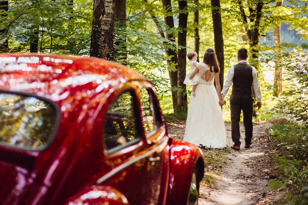 Kostenloses Foto nette eltern gehen mit ihrer kleinen tochter vor altmodischem auto