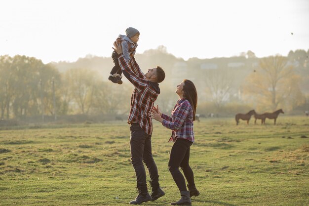 Nette Familie, die in einem Sonnenuntergangssommerpark geht