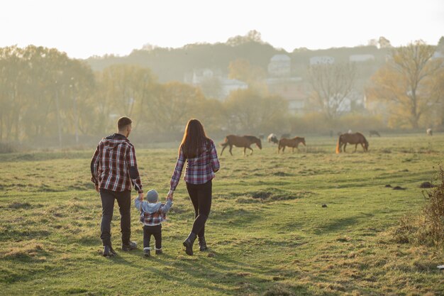 Nette Familie, die in einem Sonnenuntergangssommerpark geht