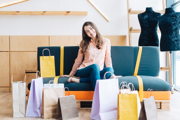 Kostenloses Foto nette frau auf sofa nahe papiertüten