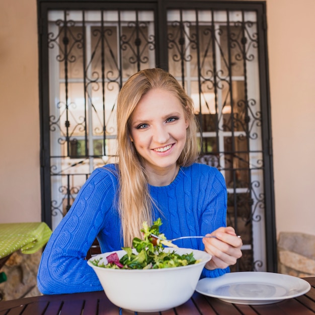 Kostenloses Foto nette frau, die draußen salat isst