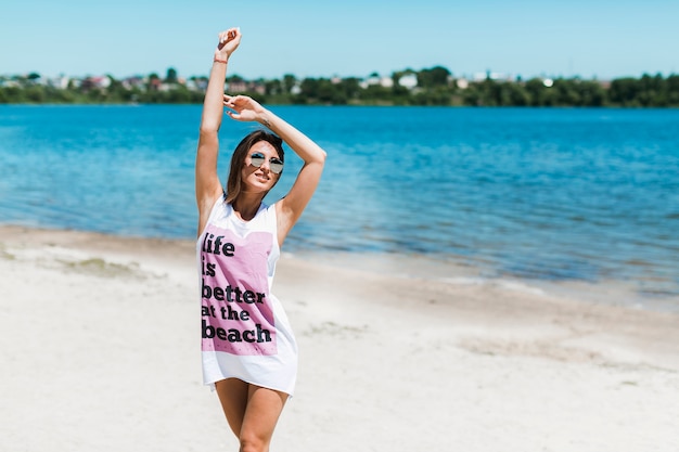 Nette Frau, die Hände oben auf Strand hält