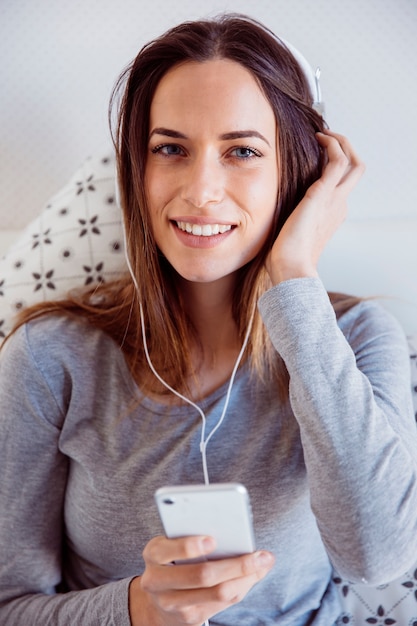 Nette Frau, die Musik im Bett hört