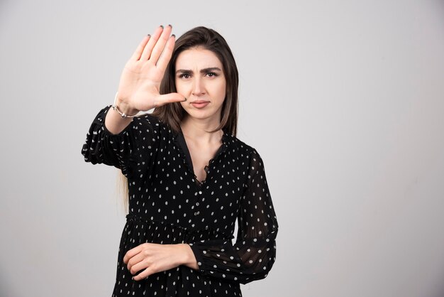 Nette Frau im schwarzen Kleid, das ihre Hand zeigt.