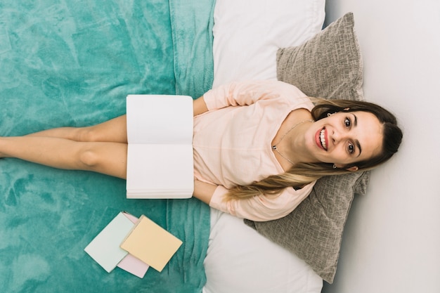 Nette Frau mit dem Buch, das Kamera betrachtet