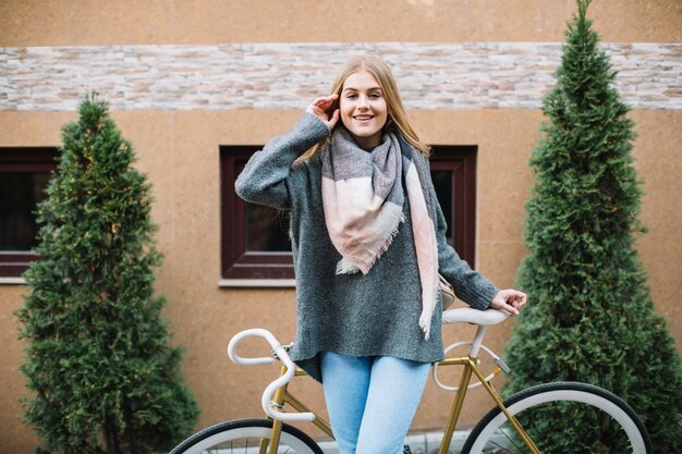 Nette Frau mit dem Fahrrad, das Kamera betrachtet