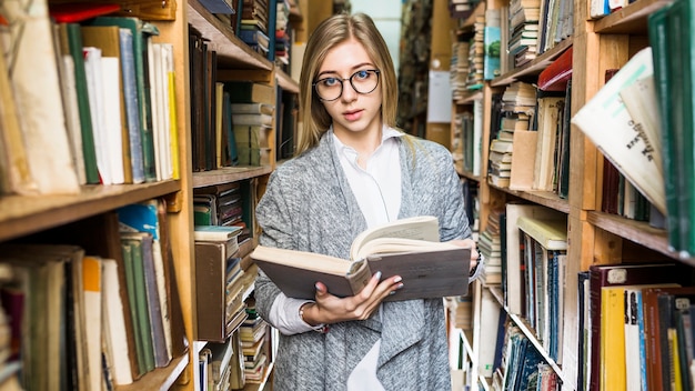 Nette Frau mit dem geöffneten Buch, das Kamera betrachtet