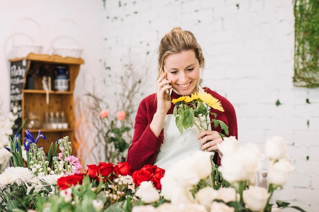 Kostenloses Foto nette frau mit der blume, die über smartphone spricht